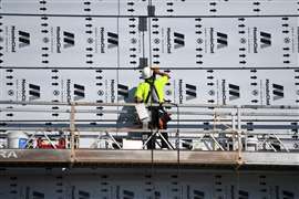 A worker installs cladding on a high-rise building 