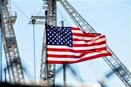 Una bandera con estrellas y rayas ondeando frente a las grúas de construcción para simbolizar la construcción en Estados Unidos.