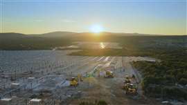 Luftaufnahme der Maschinen auf einer Solarpark-Baustelle bei Sonnenuntergang