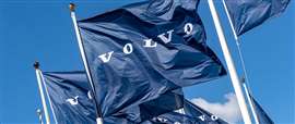 Des drapeaux bleus ornés du logo Volvo blanc flottent au vent.