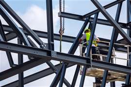 Professional installation work on a construction building site. Assemblers perform high-altitude installation works on the telescopic boom lifts platforms.