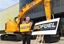 Hombre junto a una excavadora JCB amarilla sosteniendo una lata de biocombustible junto a un letrero que dice