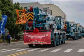 Le gru blu e gialle di Sarens della XCMG, decorate con striscioni, si sono allineate per uscire dalla fabbrica.