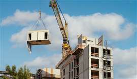 Crane lifting a wooden building module to its position in the structure. Construction site of an office building in Berlin. The new structure will be built in modular timber