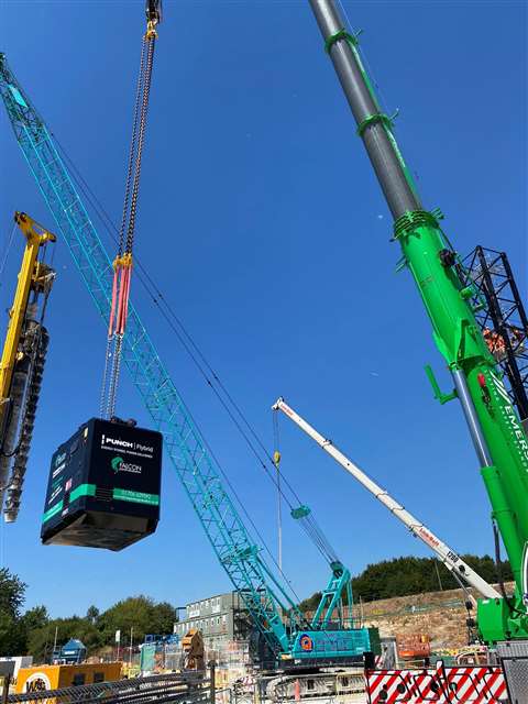 black box suspended from a green crane