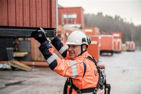 A worker helps move a shed on a site