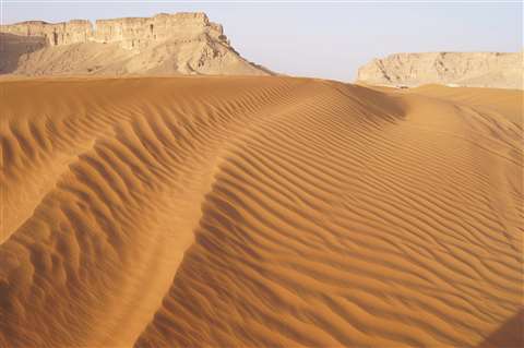 Sand dunes with rock formations in background taken at the Red Sands, Riyadh, Kingdom  of Saudi Arabia. 