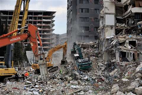 Workers clean the rubble of a collapsed building in the aftermath of a deadly earthquake in Antakya, Hatay province, Turkey