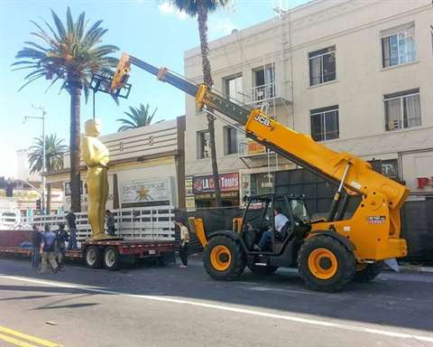 A JCB telehandler lifts and places various Oscar statues around the theater for the annual event.